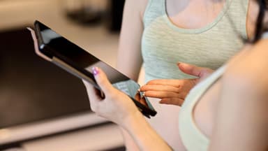 Frau zeigt kostenlose Trainingspläne auf dem Tablet