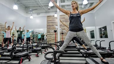 Frau unterrichtet Lagree Fitness auf dem Megaformer