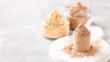 Proteinpulver im Glas und Löffel