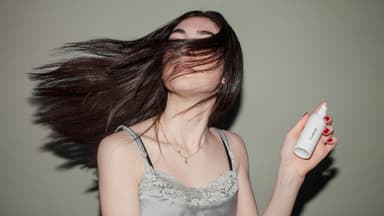 Frau hält pflegendes Haarspray