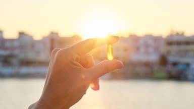 Vitamin D Kapsel zwischen den Fingern