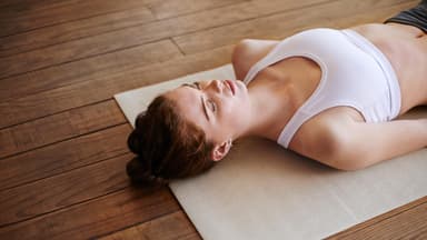 Frau liegt mit dem Rücken auf einer Yogamatte