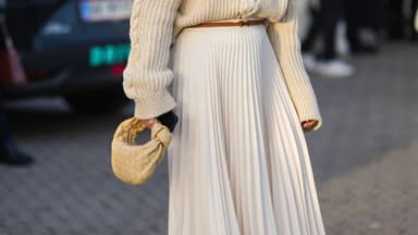 Frau mit Sonnenbrille trägt Plisseerock und Pullover