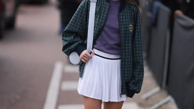 Frau mit Sonnenbrille, Collegejacke und Tennisrock