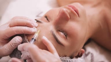 Frau bekommt Botox gegen Migräne in die Stirn gespritzt