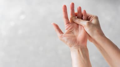 Die rechte Hand fasst an den linken Mittelfinger