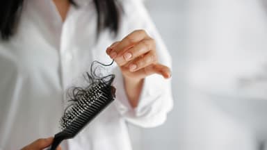 Frau zieht Haare aus der Haarbürste