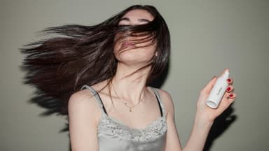 Frau mit vollem Haar und Sprühflasche in der Hand