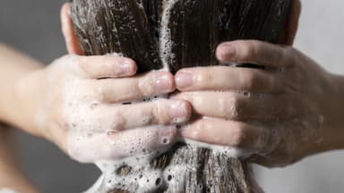 Frau wäscht Haare unter der Dusche