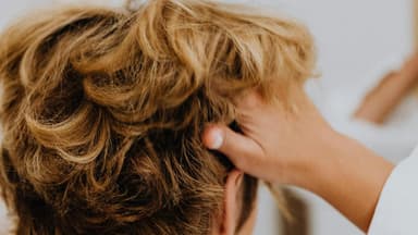 Frau geht sich mit den Fingern durch die Haare