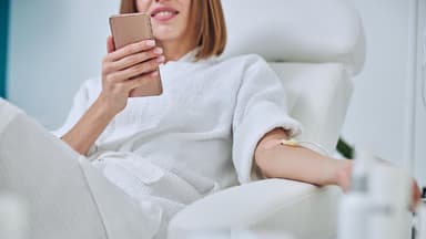 Frau am Handy bekommt eine Infusion