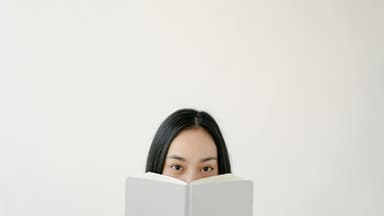 Frau versteckt sich hinter einem Buch