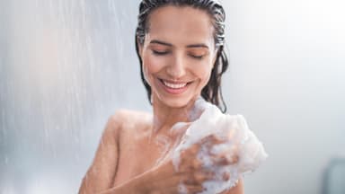 Frau seift Körper ein unter der Dusche
