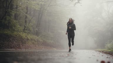 Frau beim Joggen bei Regen im Wald.