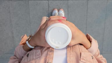 Frau hält einen Kaffeebecher in ihren Händen.