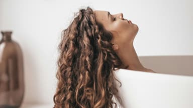 Frau mit lockigem Haar in der Badewanne