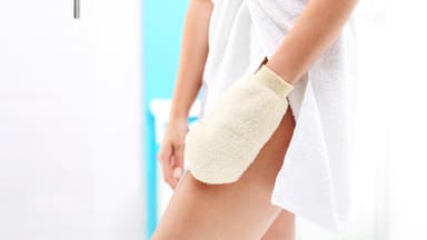Frau streicht mit einem Handschuh über ihr Bein.