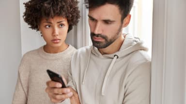 Frau schaut Partner aufs Handy
