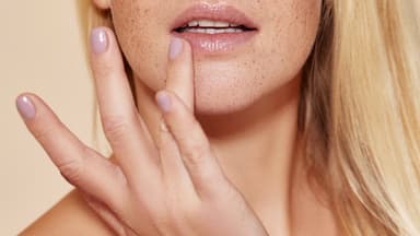 Frau verwendet Brustwarzensalbe für die Lippen