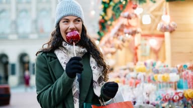 Frau isst einen Bratapfel auf dem Weihnachtsmarkt
