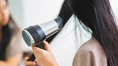 Frau föhnt sich die Haare