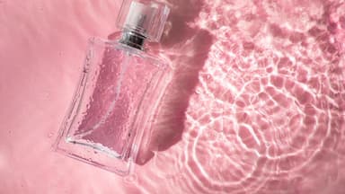 Ein Parfumflakon in seichtem Wasser liegend