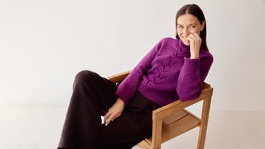 Model in fuchsiafarbenem Zopfmuster-Rollkragenpullover von Lana Grossa