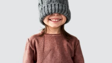 Kind in gestricktem Pullover und Mütze