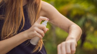 Frau sprüht sich mit selbst gemachtem Zeckenspray ein