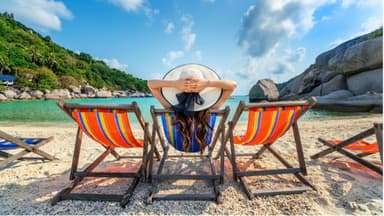 Eine Frau liegt im Liegestuhl am Meer