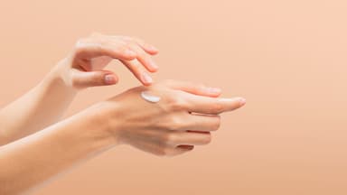 Frau trägt Handcreme mit Sonnenschutz auf ihre Hände auf