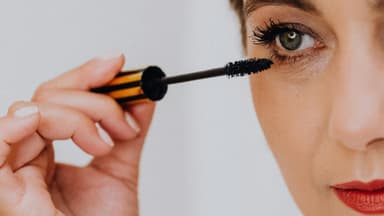 Frau trägt wasserfeste Mascara auf ihre Wimpern auf