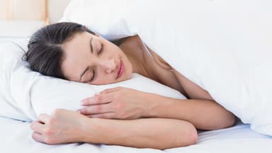 Eine Frau schläft in ihrem Bett