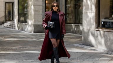 Frau trägt einen langen Mantel über einem Rock und Pullover