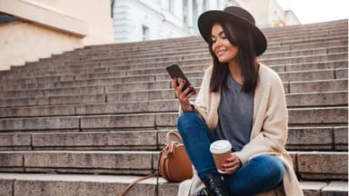 Frau sitzt auf einer Treppe und scrollt am Smartphone