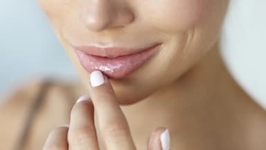 Frau mit hellen Fingernägeln berührt ihre schönen Lippen 