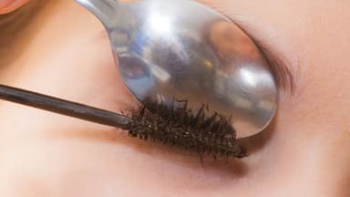 Frau biegt Wimpern mit Teelöffel