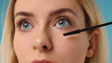 Blondine mit langen Wimpern trägt Mascara auf