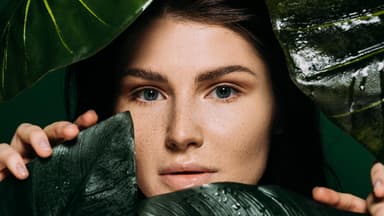 Frau hinter grünen Blättern