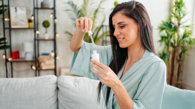 Frau im blauen Bademantel mit Serum