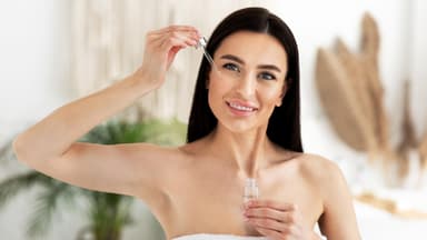 Dunkelhaarige Frau trägt Serum auf