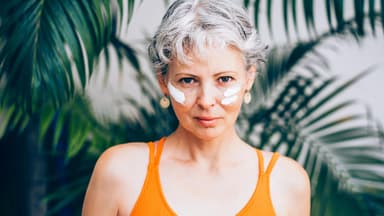 Frau mit grauen Haaren hat im Gesicht Sonnencreme aufgetragen
