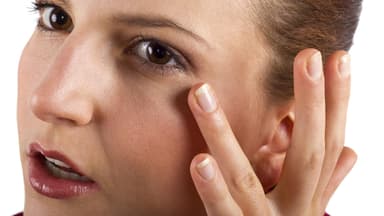 Frau berührt mit dem Finger die Augenpartie