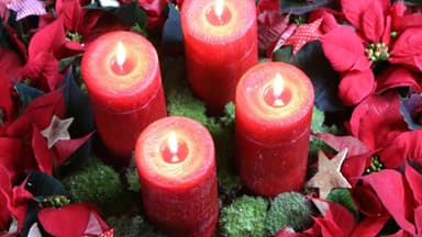 Adventskranz mit Kerzen und roten Weihnachtssternen