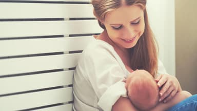 Junge Mutter hält ihr Baby in Fütterposition