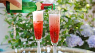 Sekt wird auf Erdbeeren eingeschenkt