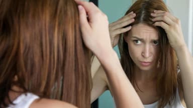 Frau prüft graue Haare – graue Haare durch Stress