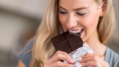 Frau isst Schokolade - ist Zucker ungesund für die Haut?