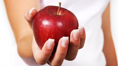 Frau mit Apfel: Gesund und fit bleiben im Homeoffice