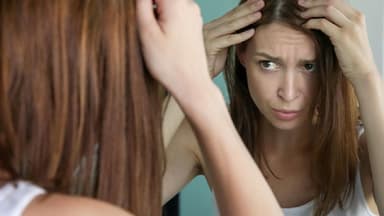 Frau prüft graue Haare – graue Haare durch Stress